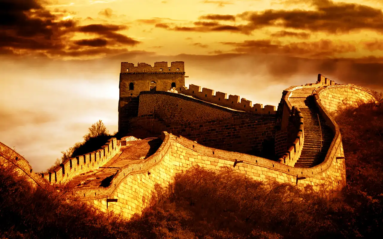 Scenic view of the Great Wall of China winding through lush green mountains under a blue sky
