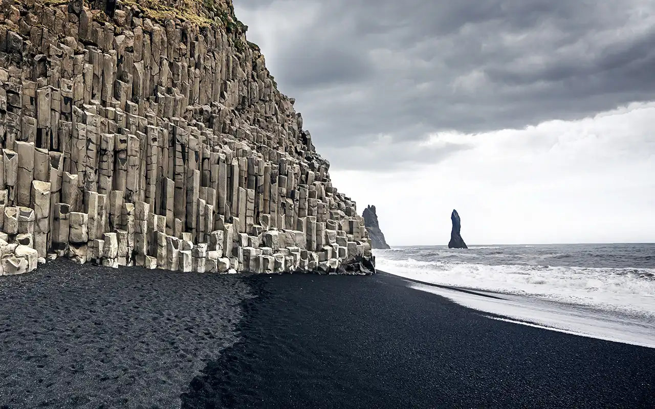 Stunning view of the black pebble Vik Beach in Iceland with vibrant Northern Lights in the sky
